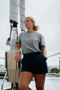 Woman standing on a boat wearing navy tech deck shorts.