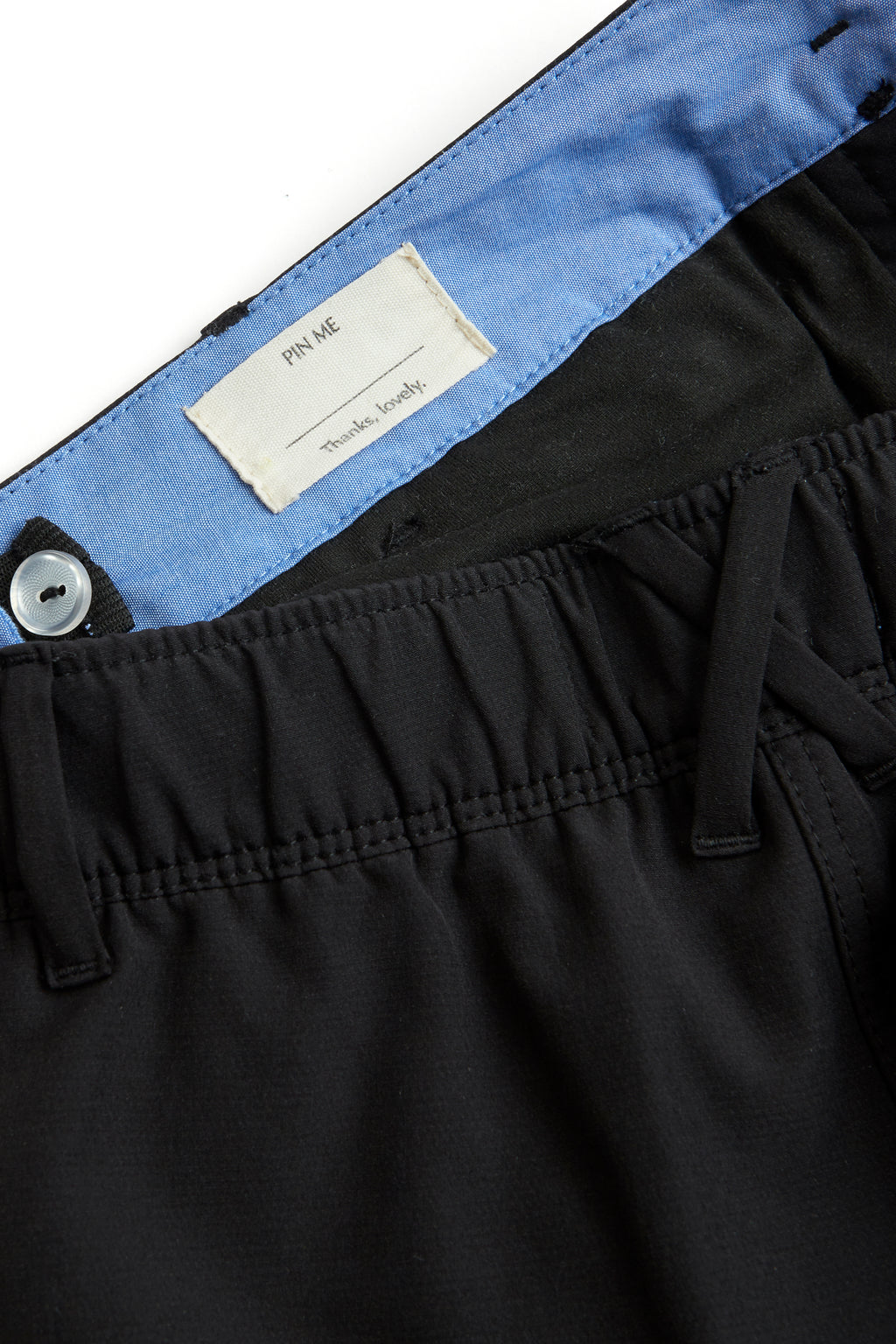 Black pants with a visible brand label on a white background. black shorts on a white background. Women's deck shorts. Yachtwear, workwear