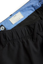 Black pants with a visible brand label on a white background. black shorts on a white background. Women's deck shorts. Yachtwear, workwear