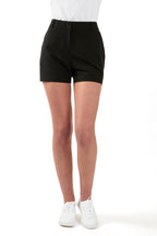 Woman wearing a white polo shirt and black chino shorts on a white background. Women's deck shorts. Yachtwear, workwear