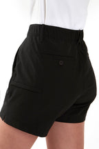 Woman wearing a white polo shirt and black chino shorts on a white background. Women's deck shorts. Yachtwear, workwear