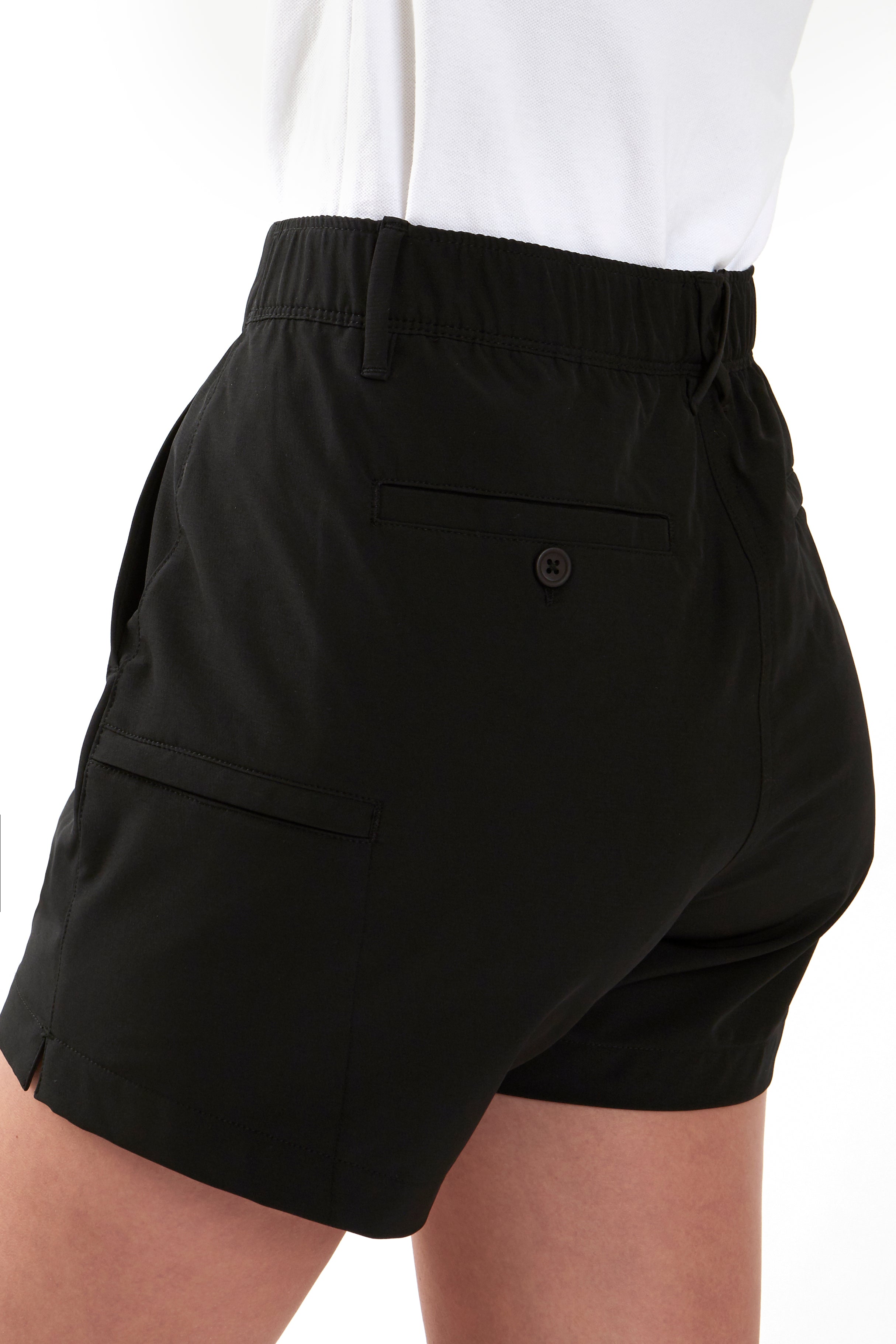 Woman wearing a white polo shirt and black chino shorts on a white background. Women's deck shorts. Yachtwear, workwear