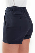 Woman wearing a white polo shirt and navy chino shorts on a white background. Women's deck shorts. Yachtwear, workwear