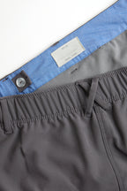 Woman wearing a white long-sleeve top and gray shorts on a white background. Women's deck shorts. Yachtwear, workwear