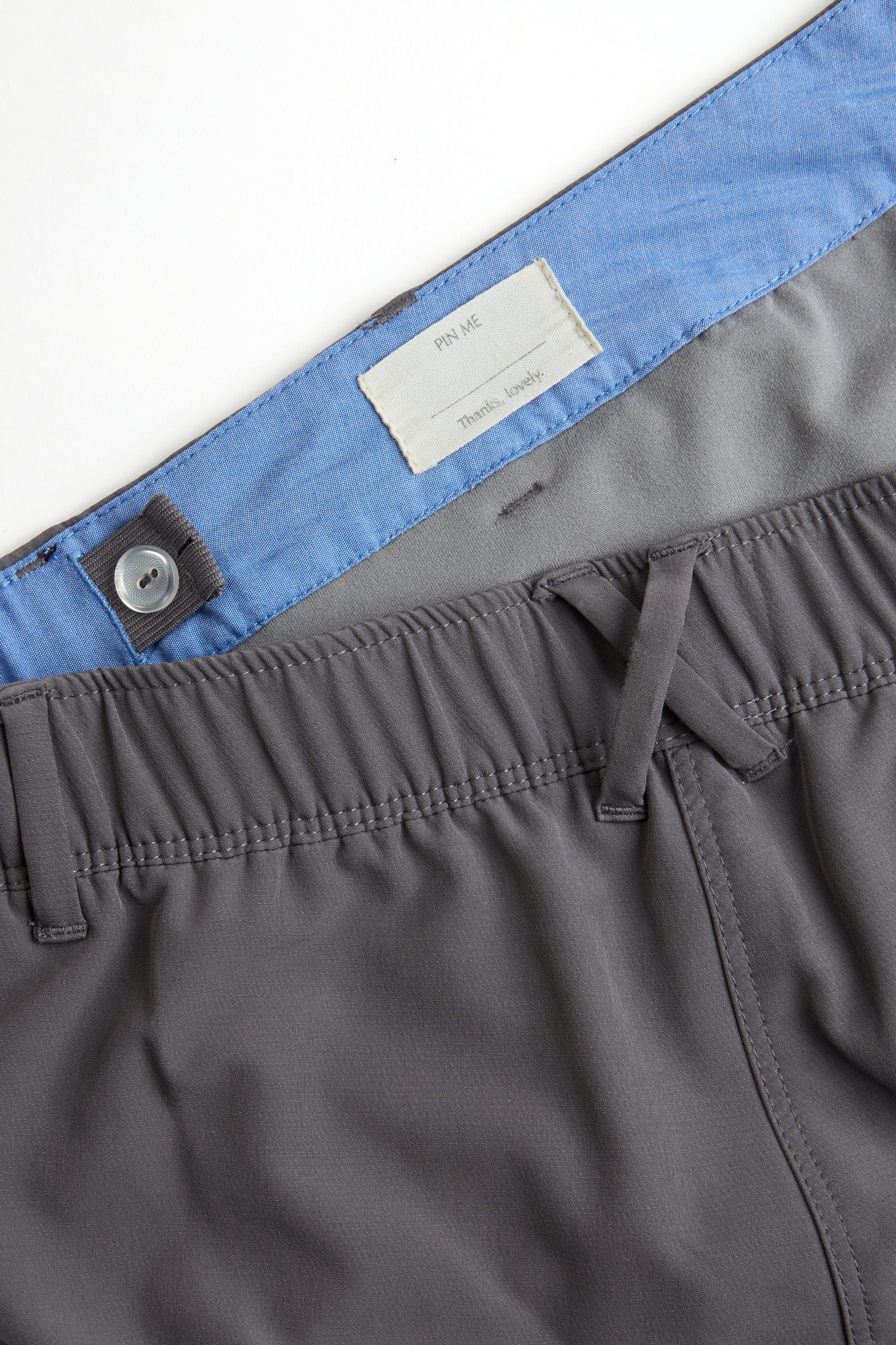 Woman wearing a white long-sleeve top and gray shorts on a white background. Women's deck shorts. Yachtwear, workwear