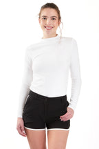 Woman wearing a white long-sleeve top and gray shorts on a white background. Women's deck shorts. Yachtwear, workwear
