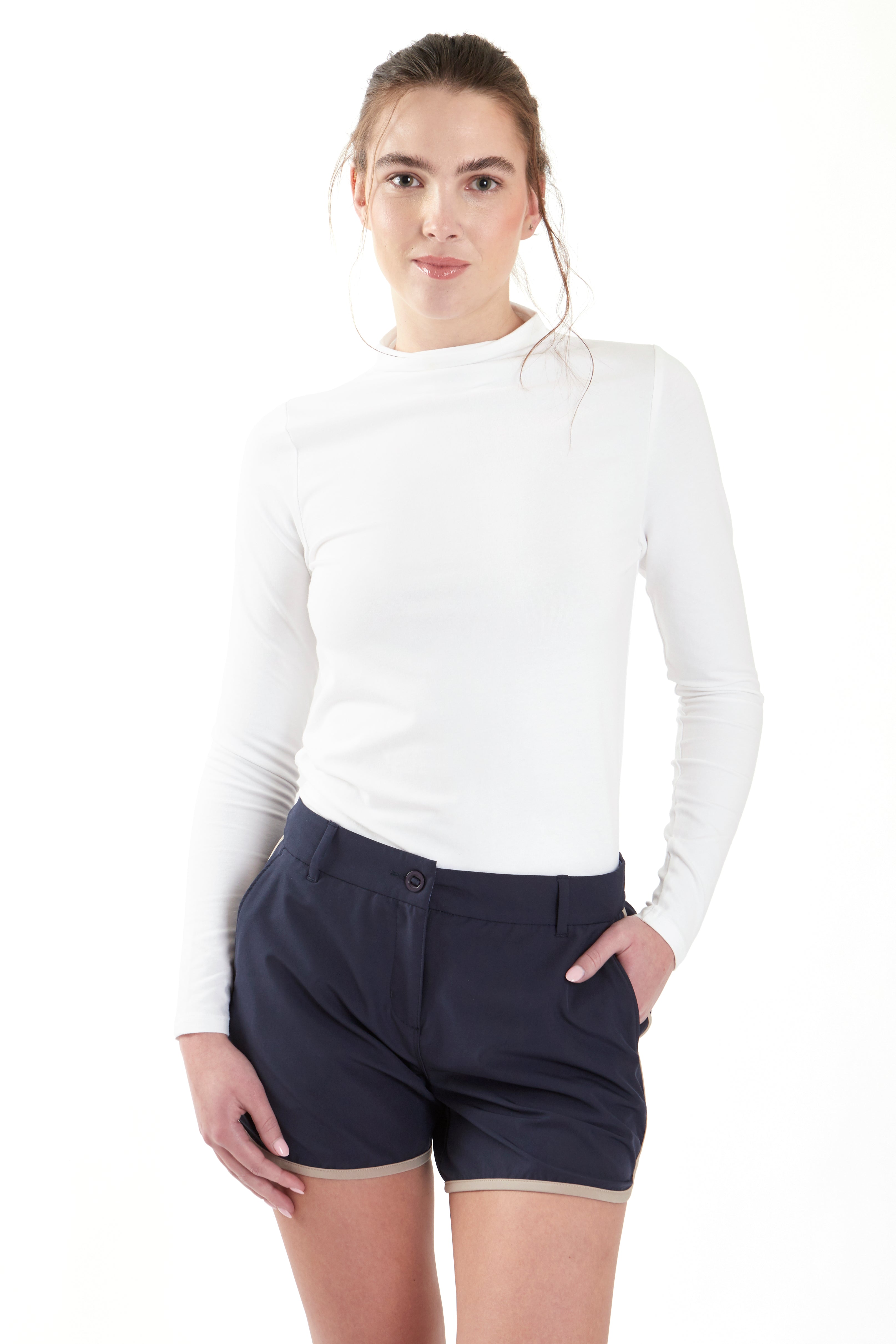 Woman wearing a white long-sleeve top and navy shorts on a white background. Women's deck shorts. Yachtwear, workwear