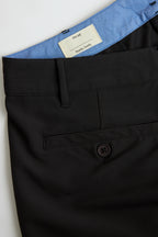 Close-up of black chino shorts with a button and label on a white background. Yachtwear. Women's deck shorts.