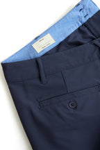 Navy blue chino shorts with a button and a visible brand label on a white background. Yachtwear. Women's deck shorts. 