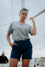Person wearing a gray t-shirt and navy chino shorts on a boat. Women's Deck Shorts. Yachtwear.
